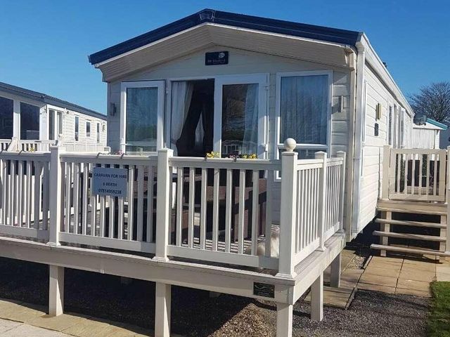 a caravan with a deck and outdoor seating at Primrose Valley Holiday Park - Holiday Accommodation 9708, Filey