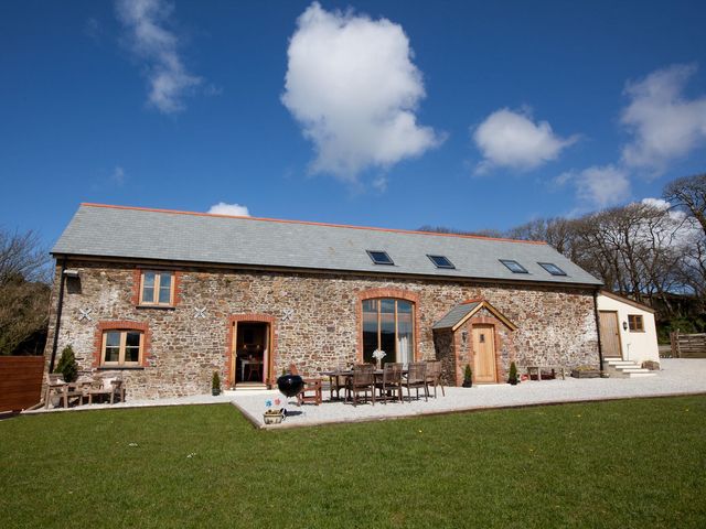 An outdoor area with a stone barn and furniture at Higher Forda in Holsworthy