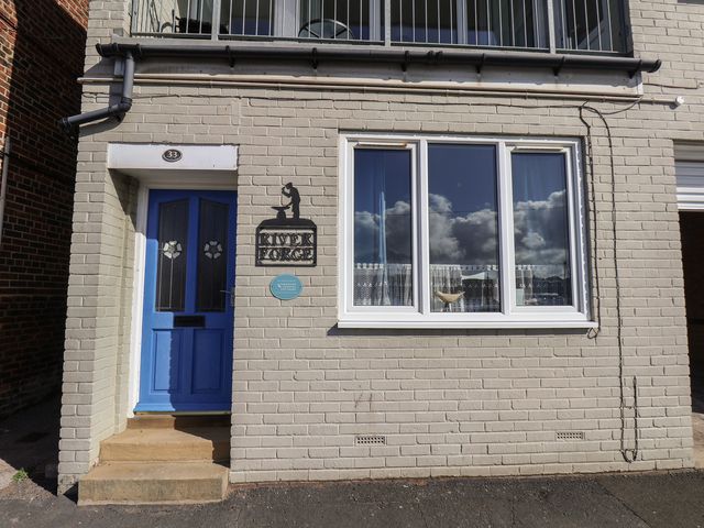 An exterior view with a blue door, window, and sign at Farriers Yard in Whitby