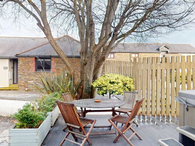 A garden with a table and chairs under a tree at Summerleaze Cottage 2 Spa in Bude