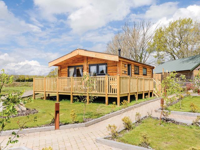 A cabin with a deck and trees in the outdoor area at Typhoon Lodge in Winchester