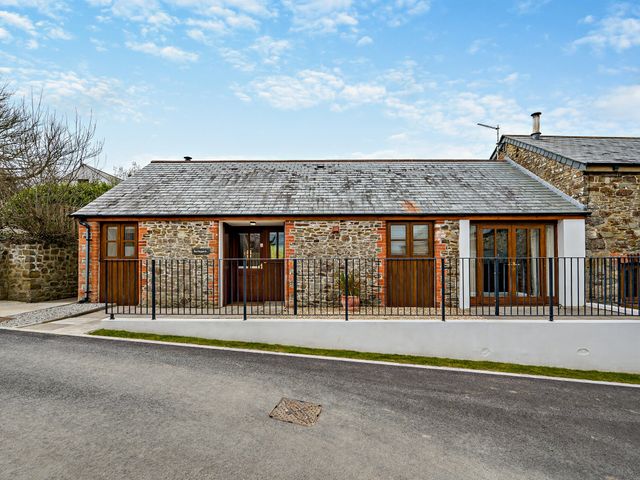 A house with a stone exterior and fence at Barley Park in Marhamchurch
