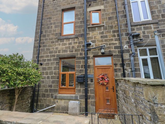 The entrance of a stone house with a wooden door and a window at 11 Bronte Street in Haworth