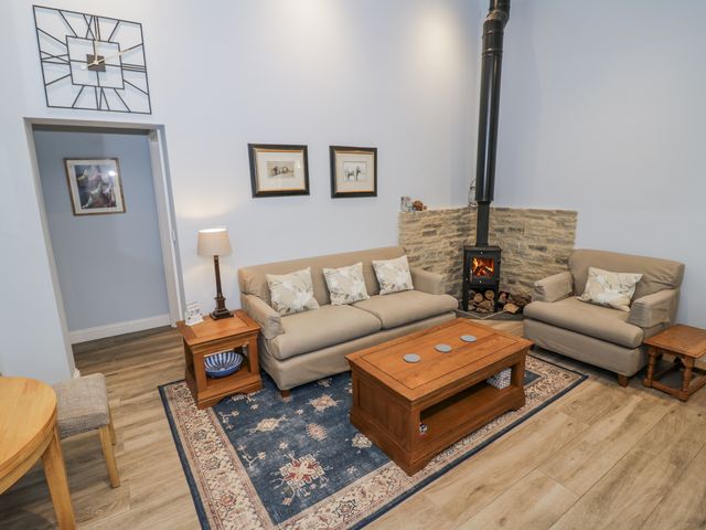 A living room with a sofa and armchair at Lily Stables in Black Bourton near Bampton, Oxfordshire