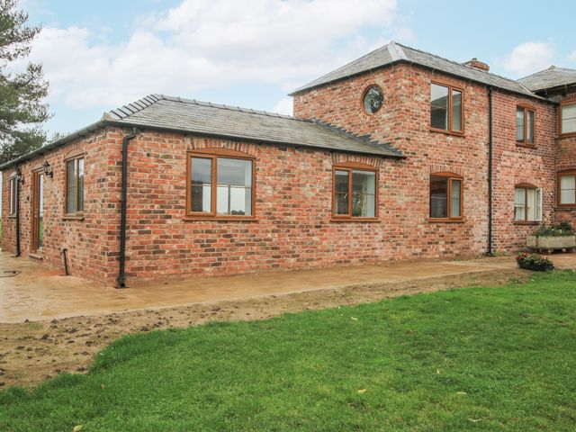 An exterior view of a brick house with a garden at Garden Cottage in Ellesmere