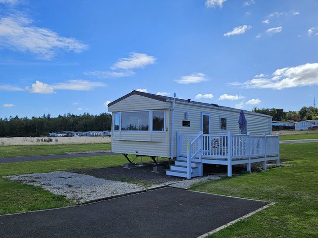 A caravan with a deck and steps at Thurston Manor Caravan Park, Pony Meadow, Dunbar