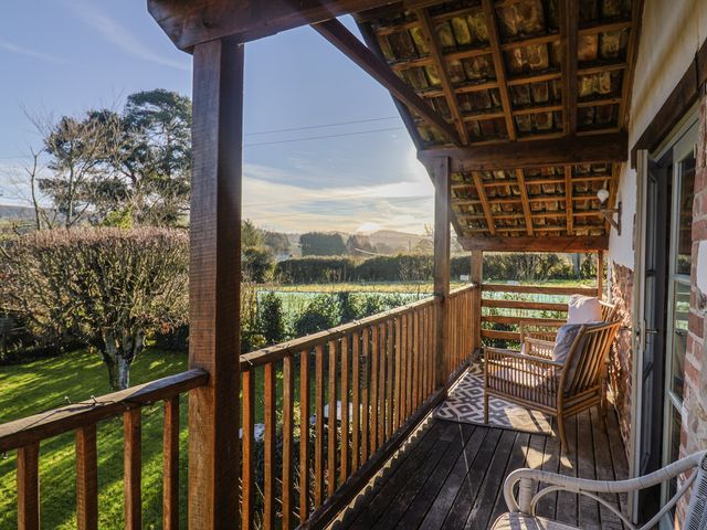 A balcony with wooden railing and chairs overlooking a garden at The Little Barn in Fluxton Nr. Ottery St Mary