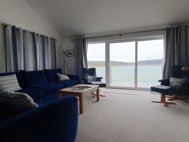 A living room with a view of the water at Gilfach Goed in Pwllheli