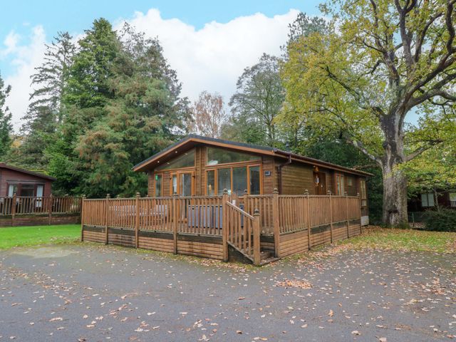A wooden cabin with a deck in an outdoor area at 5 Waterside Wood Troutbeck Bridge
