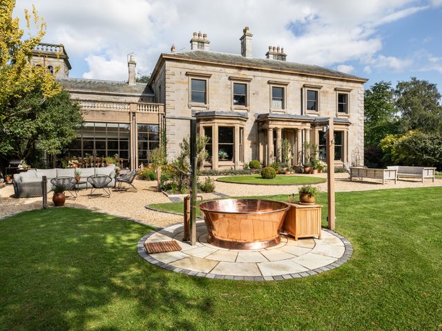 A garden with a copper bathtub and outdoor seating at The Country House Cumbria Castle Carrock