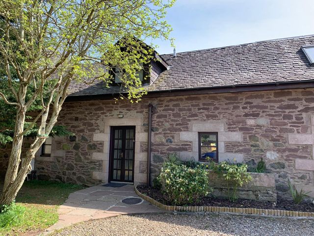 An exterior view of a stone building with a door and window at The Cottage in Perth