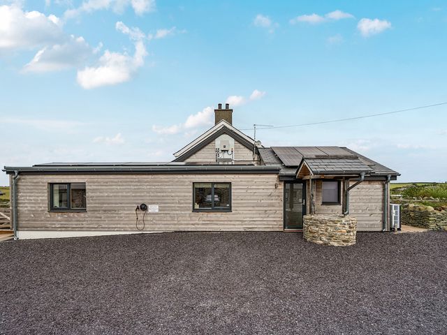 A house with solar panels and a gravel driveway at 2 Trem Y Mor in Llanfwrog near Llanfachraeth