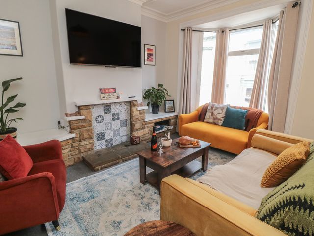 A living room with a television and sofas at Captain Jacks in Whitby