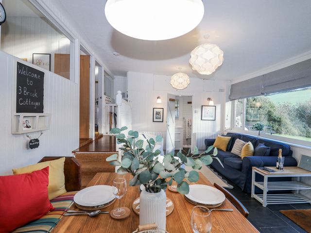 A dining room with a table and sofa at 3 Brook Cottages Hope Cove