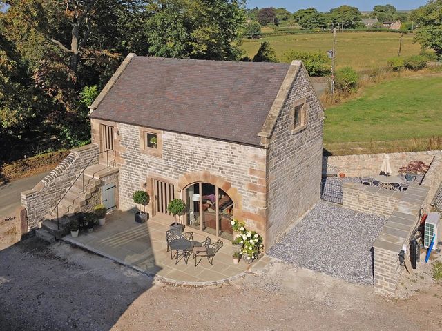 An outdoor area with a stone building and seating at Lane House Farm Barn Butterton