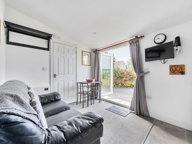 A living room with a sofa, table, and chair at The Nook in Praa Sands