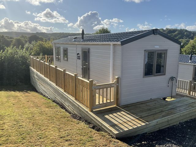 A caravan with a wooden deck in a rural setting at caravan NEW Uplyme