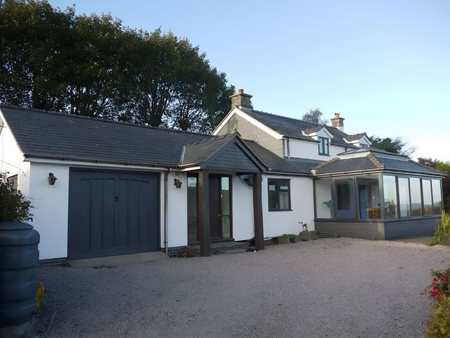 A house with a garage and conservatory at Tranquil Cottage in 