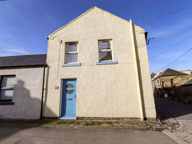 A yellow house with a blue door and windows at Corner Cottage in Seahouses