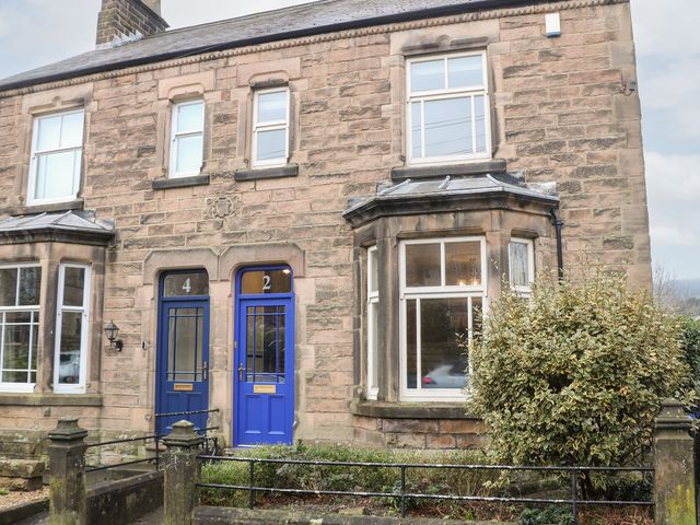 A stone house exterior with blue doors at Dorset Villas in Matlock