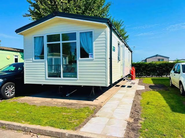 A mobile home with a car parked beside it at a holiday park