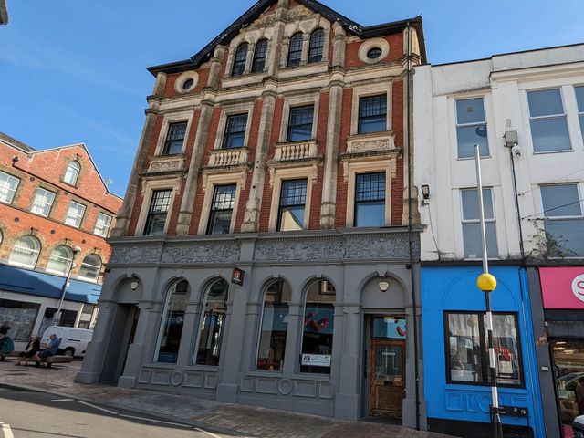 A historic building with arches and detailed brickwork in a street setting