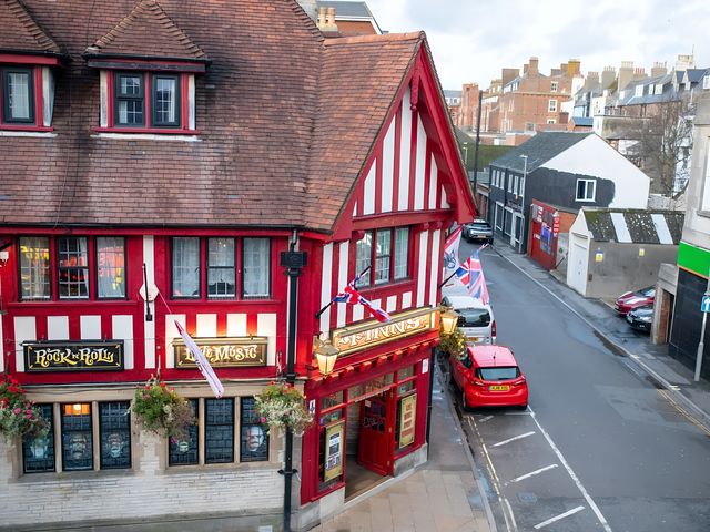 A pub with a red and white exterior on a street at Red Rose Apartment 