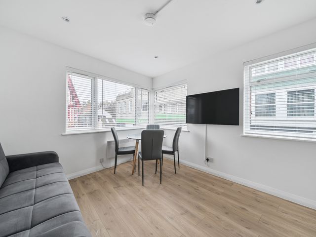 A living room with a sofa and dining table at Red Rose Apartment in Weymouth