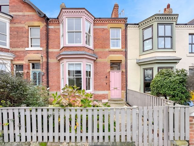 A house exterior featuring brick walls and a pink front door at Victorian Beach House