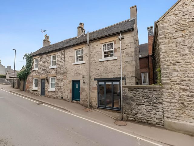 A house with a stone exterior on a street at Belmont Cottage in Matlock