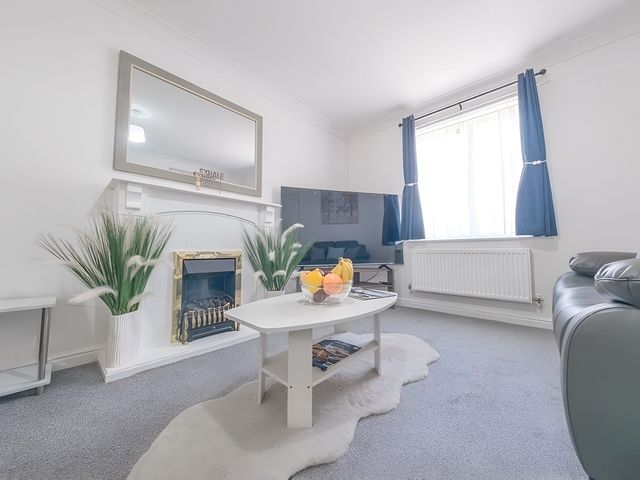 A living room with a fireplace and television at Bluebell Close in Corby