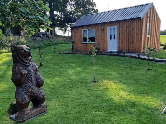 A garden with a wooden cabin and a bear statue at Taigh Nam Moireach in Inverness