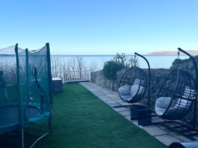 An outdoor garden area with a trampoline and hanging chairs at Blue Haven Penmaenmawr