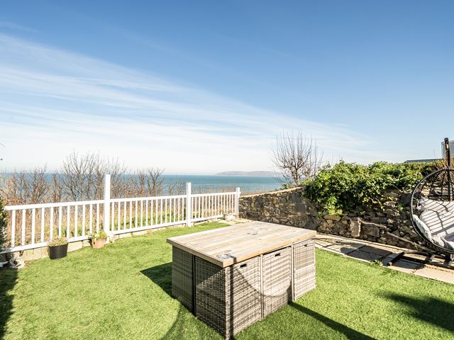 A garden with a table and chairs overlooking the sea at Blue Haven in Penmaenmawr