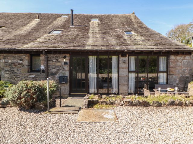 A garden view of a stone cottage with patio furniture at Tullythwaite Barn in Kendal