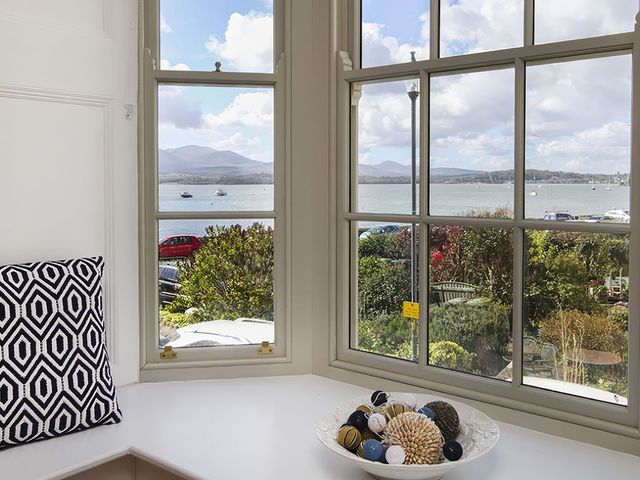 A living room with a view of the sea and mountains at Tri Raglan Mawr in Beaumaris