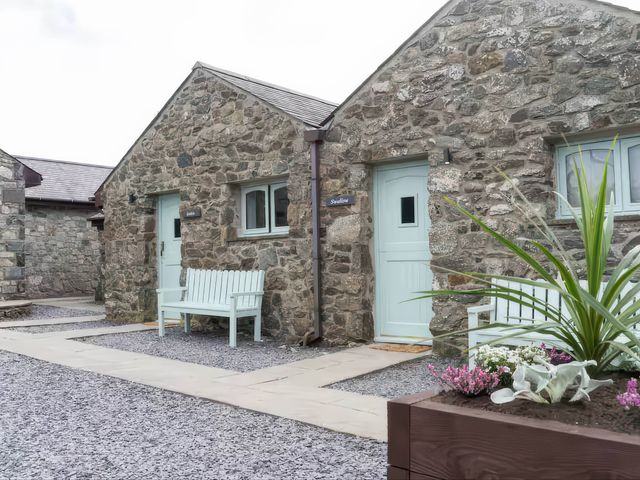 An outdoor area with stone walls and a bench at Black Bird Cottage Llangaffo
