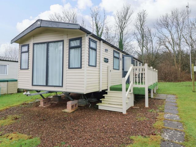 A mobile home with a deck and stairs at Caravan number 77