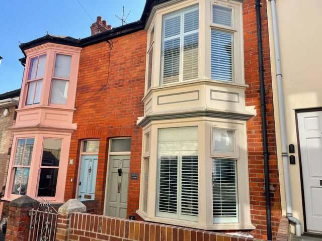 An exterior view of a house with pink and white windows at Seahorse Cottage in Weymouth