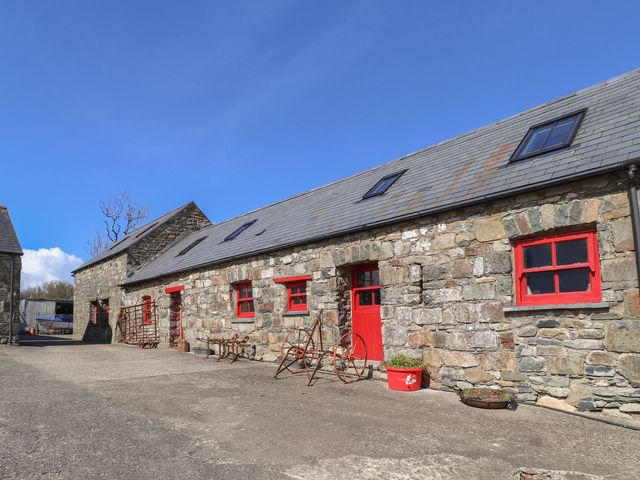 An outdoor area with stone buildings and red doors at Ty Gwartheg in Newport