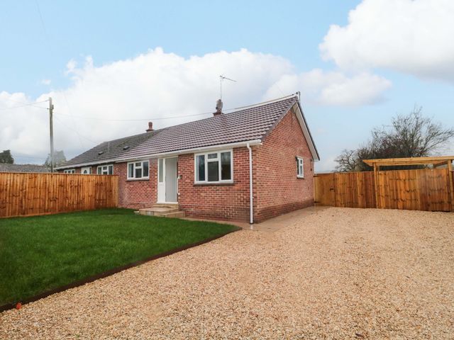 A bungalow with a lawn and gravel driveway at 2 Stroud Bungalows
