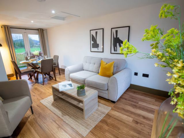 A living room with a sofa and dining area at Fir Cottages in Llanrwst