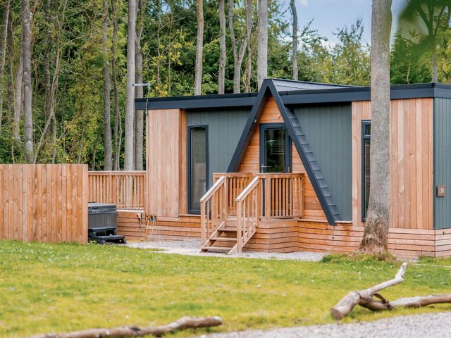 A wooden cabin with stairs and decking in an outdoor area at Tennyson Spa (Pet) Louth