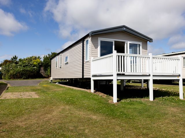 A mobile home with a deck and grass area at No 19 Cliff top park Hartlepool