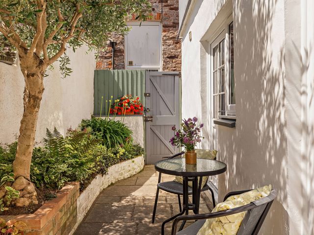 A garden with a table and chairs alongside plants at Ivy Cottage in Dartmouth