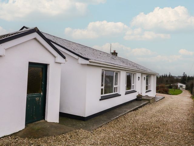 A house with a green door and windows at Bungalow Falcarragh in Falcarragh, County Donegal