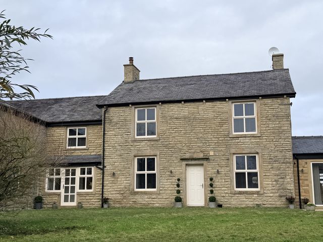 A stone house with windows and a door surrounded by grass at The Farm House in Wigglesworth near Settle