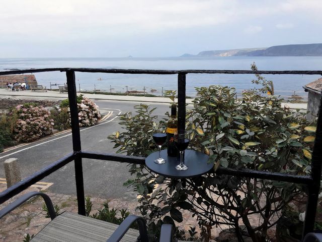 A balcony with wine glasses and a bottle overlooking the sea at Cove Retreat in Sennen Cove