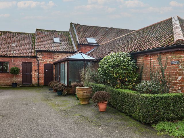An outdoor area with a conservatory and hedges at Winston Lodge in Beccles