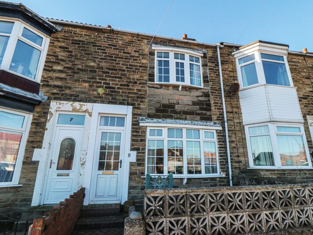 A front view of a stone house with doors and windows at Cattersty Cottage in Carlin How